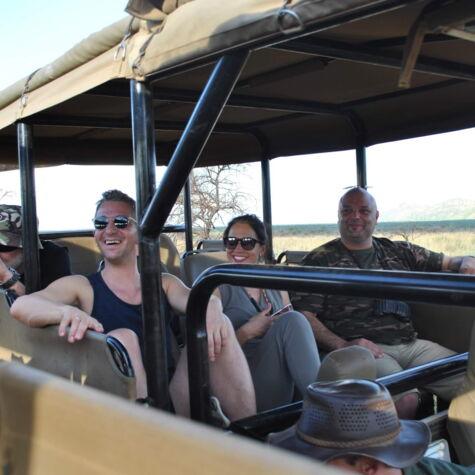 Mitarbeiter sitzen lächelnd in einem Safari-Jeep und genießen eine abenteuerliche Fahrt durch die Wildnis während eines Firmenausflugs