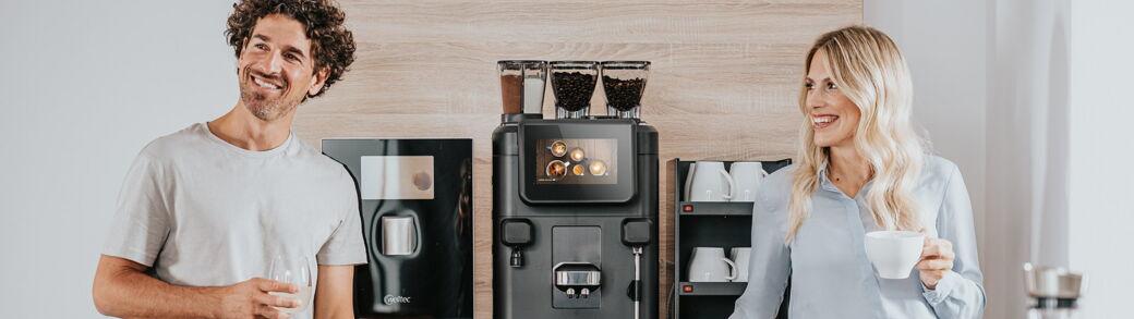 Zwei Kollegen stehen an einer Kaffeebar ausgestattet mit Kaffeevollautomat und Wasserspender
